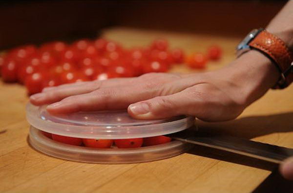 Cut small foods like cherry tomatoes by using two plastic lids. It'll save you time and protect you from any nasty cuts. 